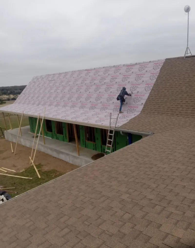 Worker preparing underlayment for a metal roof installation in The Dalles